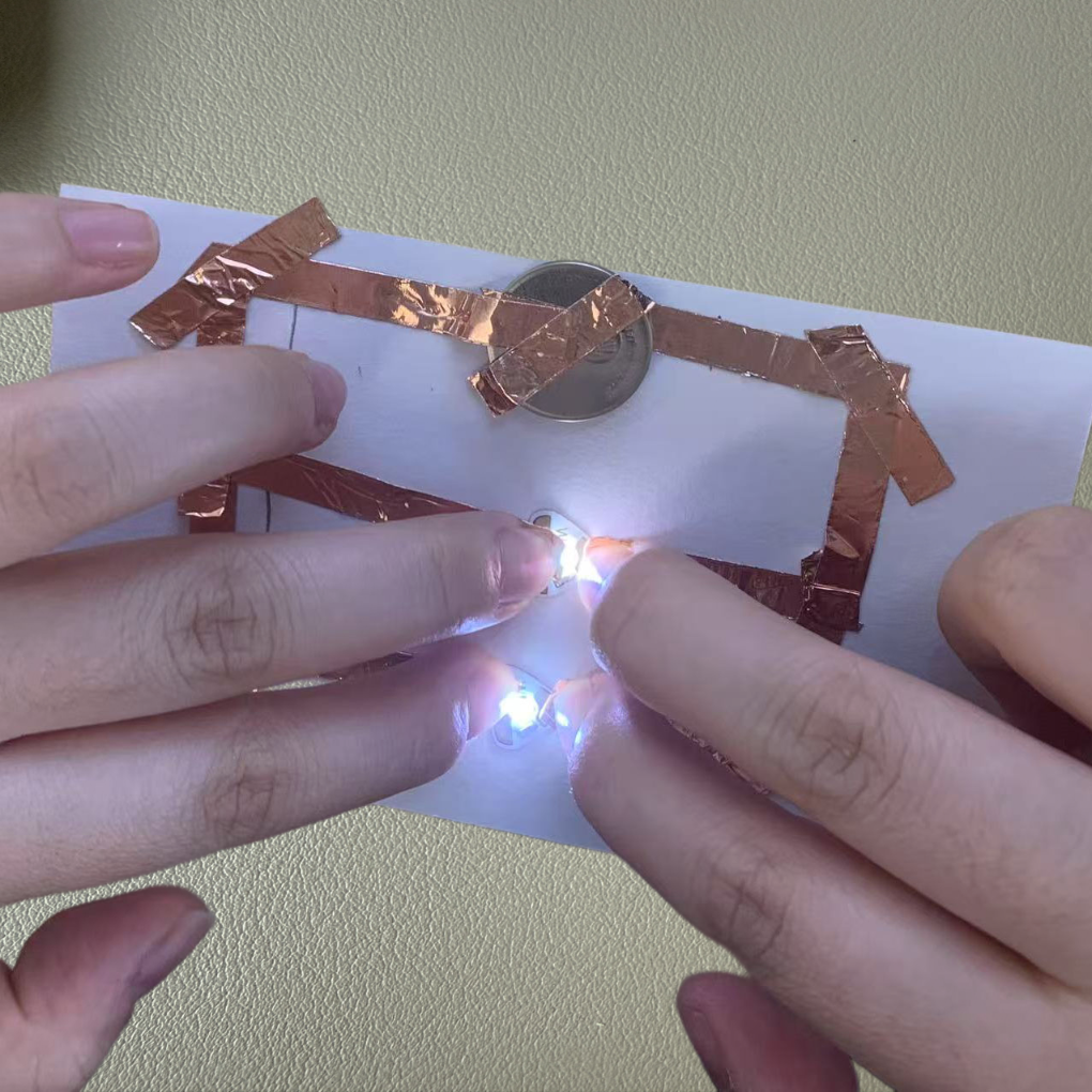 I pressed the connections to test the parallel circuit, and both LEDs lit up brightly, proving the design works perfectly.